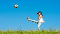Girl kicking soccer ball on meadow