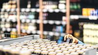 Retail worker filling shelf with drinks in grocery store or customer taking can of beer or soda. Staff at supermarket stocking s