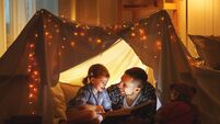 happy family father and child daughter reading a book  in  tent at home
