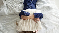 Too lazy to get out of bed, a woman covers her face with a pillow