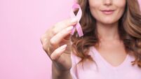 Woman in pink sweater with pink ribbon supporting breast cancer awareness campaign