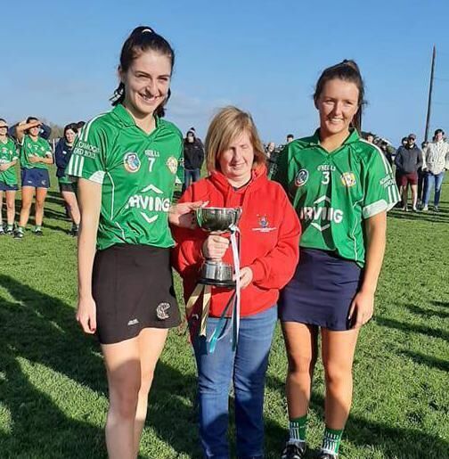 Aghada Joint Captains Ava Rose Boylan and Sarah Walsh receiving The Junior B cup from Mary Mc Sweeney treasurer Cork Camogie Board 