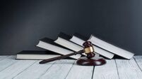 Law concept - Open law book with a wooden judges gavel on table in a courtroom or law enforcement office isolated on white backg