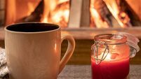 Big mug with hot tea, and a candle , wool scarf, near cozy fireplace, hygge, home sweet home.