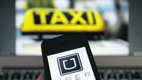 An illustration picture shows the logo of car-sharing service app Uber on a smartphone next to the picture of an official German