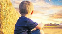 Child sitting on bales of straw