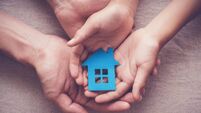 Adult and child hands holding paper house, family home and homeless shelter concept