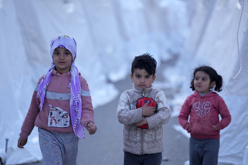 Children walk between tents, in Aslanli, southeastern Turkey. Tens of thousands of people who lost their homes in a catastrophic earthquake huddled around campfires in the bitter cold and clamored for food and water. (Picture: AP Photo/Kamran Jebreili)