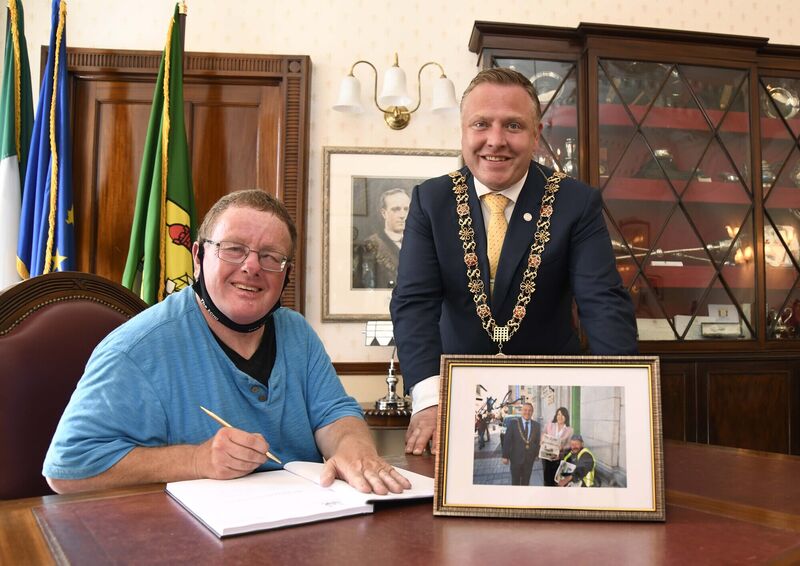David Hogan, Echo Boy in Cork, signing the visitors book at City Hall after being presented with a framed signed photograph of himself with the US Ambassador and the Lord Mayor, Cllr. Colm Kelleher, which the Former Lord Mayor presented to him.