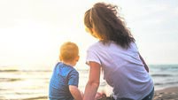 Mother with little baby boy at the beach on sunset