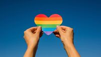 Woman holds in hands a heart in the colors of the rainbow. Young beautiful girl. LGBT history month. Pride Month. Lesbian Gay Bi