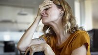 Portrait of crying woman with hands on her face while sitting indoors