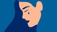 Sad young girl is crying on a blue background.