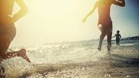 Brothers and sister running on beach on sunset