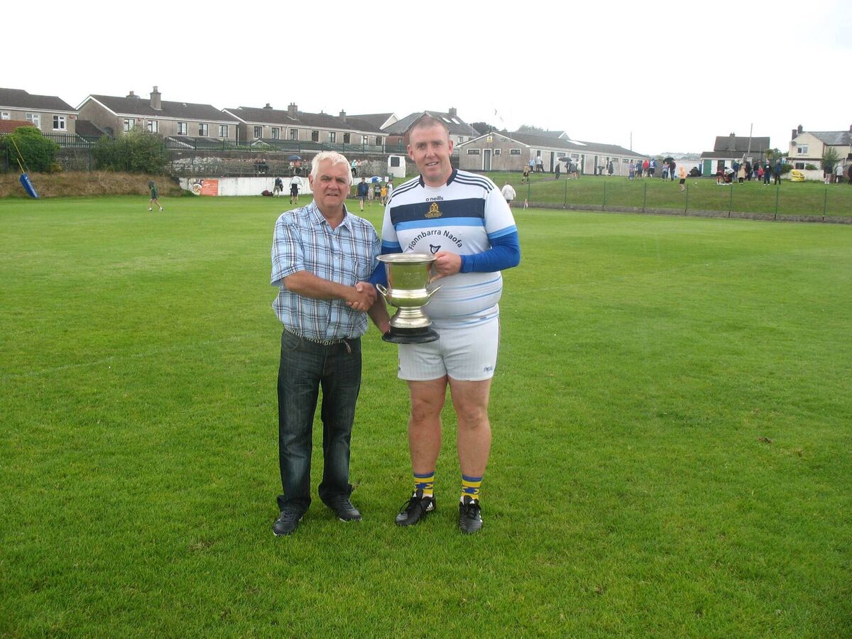 Seandún chairman Michael Higgins presenting the trophy to St Finbarr's Junior B winning captain Pat Kenneally.