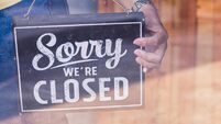 Woman Holding up a shop sign saying: Sorry we're Closed