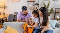 Daughter Packing Her Backpack For School With The Help Of Her Parents