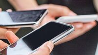 Shot of a group of unrecognizable businesspeople using their cellphones in a modern office
