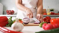 Homemade cooking. Woman in the kitchen cutting red onions on a c