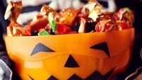Boy in skeleton costume holding bowl full of candies