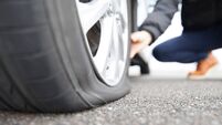 man touching a flat tire on the roadside