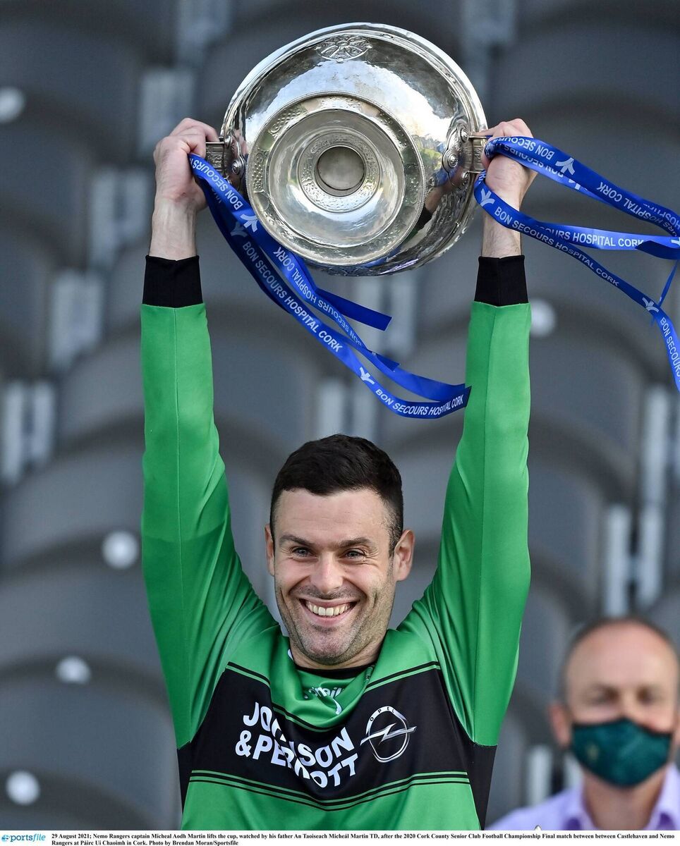Micheál Aodh Martin lifts the Andy Scannell Cup, watched by his father, An Tánaiste Micheál Martin TD, after the 2020 Bons Secours Hospital Cork Premier SFC final between Nemo Rangers and Castlehaven. Picture: Brendan Moran/Sportsfile