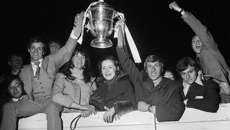 Cork Hibernians' captain Dave Bucuzzi, right, holding the FAI Cup with hat-trick hero Miah Dennehy amid a group of jubilant supporters. Cork Hibernians' captain Dave Bucuzzi, right, holding the FAI Cup with hat-trick hero Miah Dennehy amid a group of jubilant supporters.