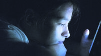 Teenager sending email from smart phone in her bed