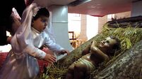 A little girl is held close to a statue