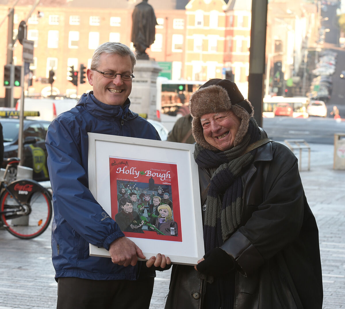 John Dolan presents late newspaper vendor Michael O'Regan with a framed copy of the Holly Bough 2016 front page, signed by comic book artist Will Sliney. Picture: Larry Cummins