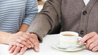 Close Up Of Woman Sharing Cup Of Tea With Elderly Parent