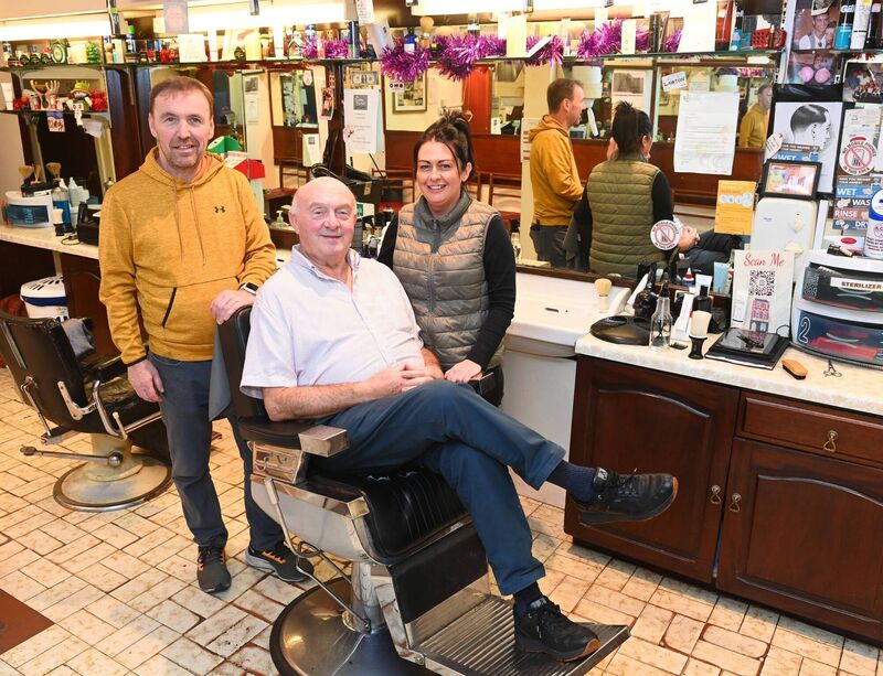 Staff members Donncha O'Connell (25 years service) and Amy O'Donovan (2.5 years service) with 'Baldy Barber' Mick Moriarty in the chair at the premises. Pic Larry Cummins