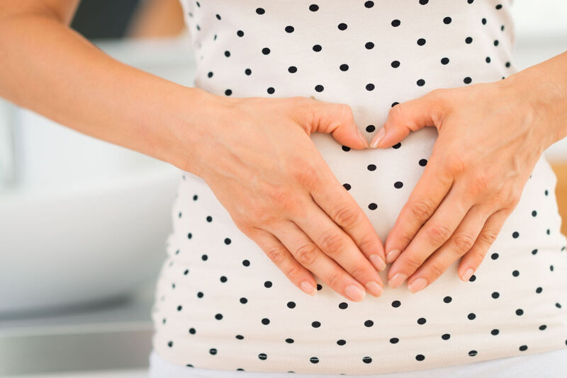  A generic photo of a woman creating a heart shape over her gut. 