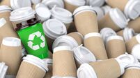 Recycling  sign on one of the heap of many empty paper coffee cups.