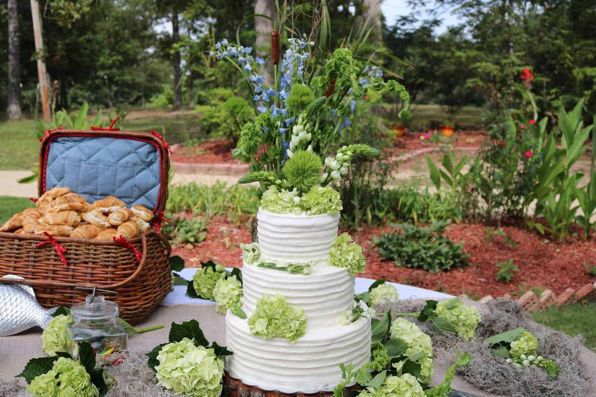 Outdoor wedding cake with green floral accents. 