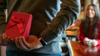 Man surprising woman with a gift while celebrating Valentines at a restaurant