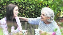Teenage Granddaughter Relaxing With Grandmother In Garden