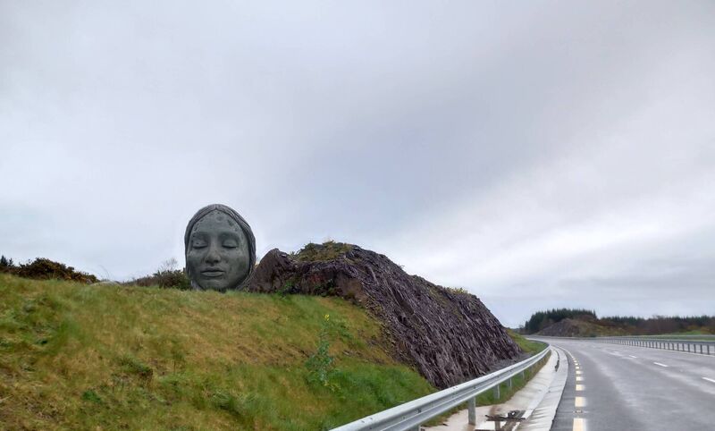 The bust of a bronze age girl whose remains were uncovered during excavations to build the N22 bypass is represented here at Kilnagurteen, between Coolavokig and Carrigaphooka, on the east bound lane of the bypasss. It was designed and crafted by artist Sarah Goyvaerts under the Per Cent for Art scheme. The bust of a bronze age girl whose remains were uncovered during excavations to build the N22 bypass is represented here at Kilnagurteen, between Coolavokig and Carrigaphooka, on the east bound lane of the bypasss. It was designed and crafted by artist Sarah Goyvaerts under the Per Cent for Art scheme.