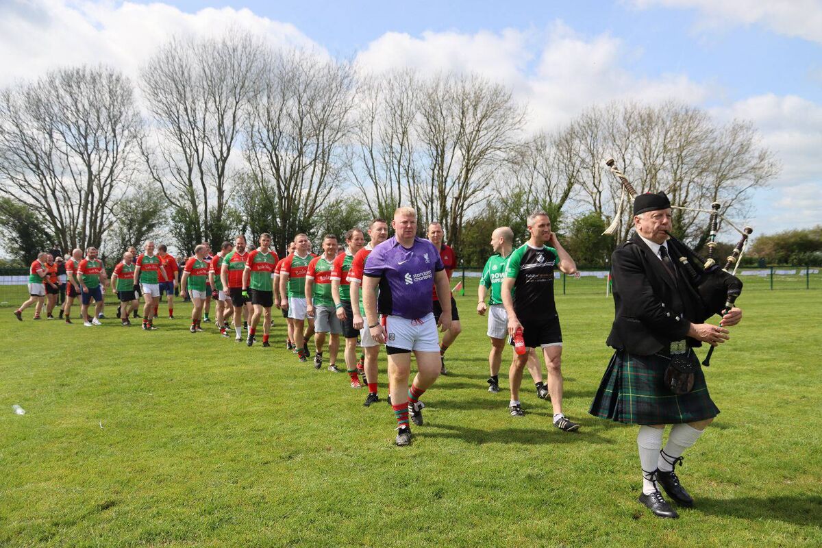 The locals and blows ins parade behind the lone piper at Ballinora's 100th birthday celebrations. 