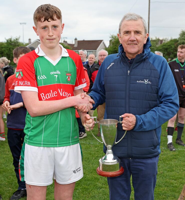  James O'Sullivan, BallinoraCaptain , receives the Cup from Michael O'Mahony, Chairperson Rebel Og.