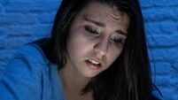 Dramatic portrait of sad scared young woman on smart mobile phone suffering cyber bullying and harassment. feeling lonely, depre