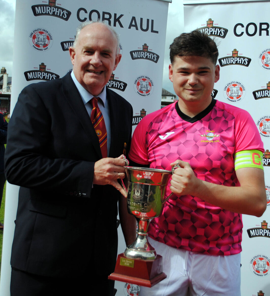 Dan Flynn (Cork AUL) presents the President's Cup to Dave Og Coleman (Strand B), following their 3-1 penalty shoot-out victory over Coachford B after a 2-2 draw. Dan Flynn (Cork AUL) presents the President's Cup to Dave Og Coleman (Strand B), following their 3-1 penalty shoot-out victory over Coachford B after a 2-2 draw.