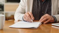 Hands of senior retirement woman writing a finance savings budget plan on paper or legal trust fund for after her funeral. Elder