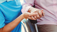 Nurse consoling a senior woman in the nursing home holding her hand in the nursing home