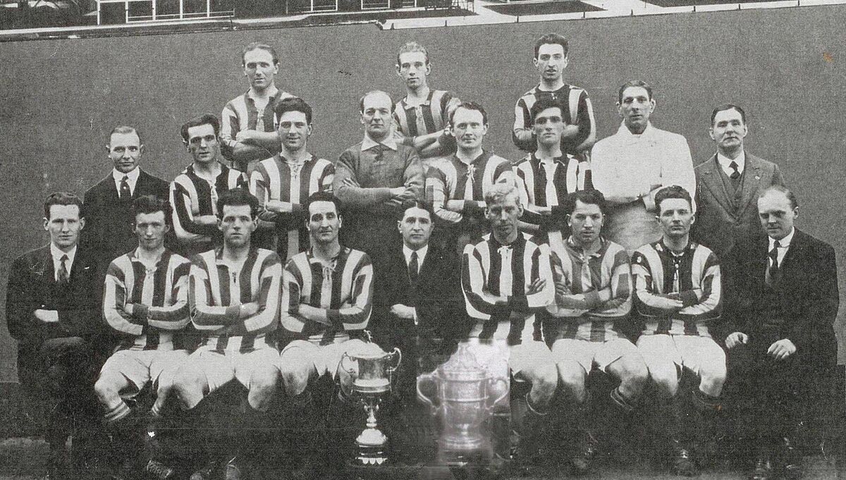 Fordsons, FAI Free State Cup winners in 1926, with the trophy. Back: Paddy Kelly, Mal McKinny, Dinny Driscoll. Middle: L R Dalton (finance), Sally Connolly, Barney Collins, Bill O’Hagan, Jack Carabine, Jack Baylor, Jack Finn (trainer), J Leddy (comm). Front: Percy Rocky (treas), Billy Hannon, Jack Sullivan (capt), Frank Brady, H Scott (Manager Henry Fords), Harry Buckle, Dave Roberts, Paddy Barry, P J Gilhooley (sec).