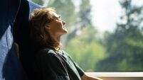 Young beautiful woman wearing glasses sitting in a chair in a high-speed train relaxing while traveling