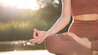Woman practicing Padmasana on yoga mat on wooden pier near pond, closeup with space for text. Lotus pose
