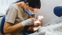 Group portrait of two people, woman dentist making treatment in modern clinic for man. Medical concept photography indoors for d