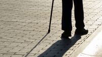 Silhouette of man walking with a cane, long shadow on pavement