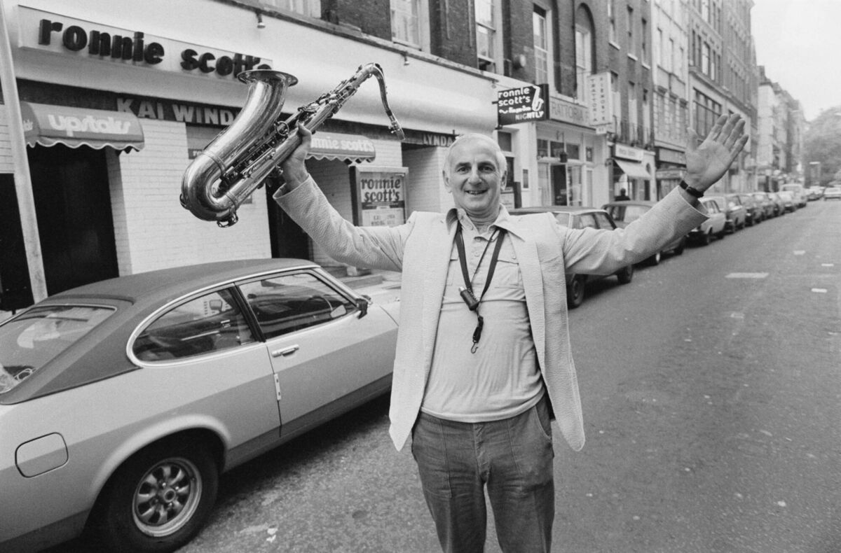 British jazz musician Ronnie Scott (1927 - 1996) poses with a saxophone outside his jazz club in Soho, London, October 1979. (Photo by Evening Standard/Hulton Archive/Getty Images)